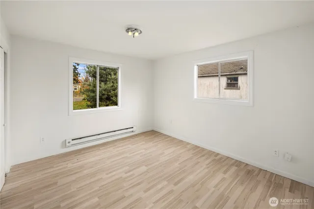an empty room with wooden floor and windows