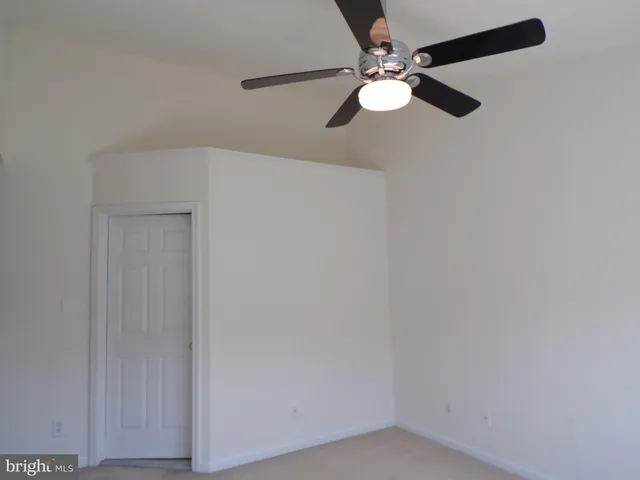 an empty room with a fan & a ceiling fan