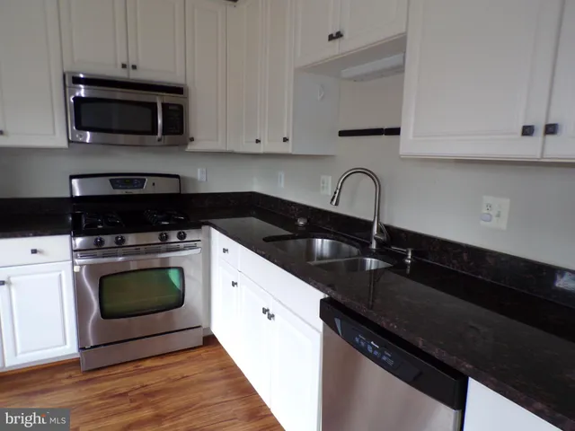 a kitchen with granite countertop white cabinets and black appliances