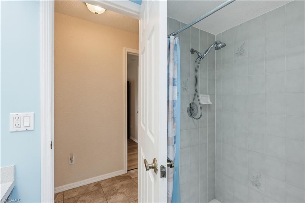25378 Rupert Road Punta Gorda, FL 33983 - Photo 41 of 50 Shower stall featuring light gray tile surround, a chrome showerhead with handheld sprayer, and a built-in soap dish