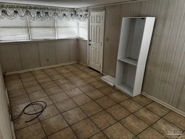 an empty room with wooden floor cabinet and windows
