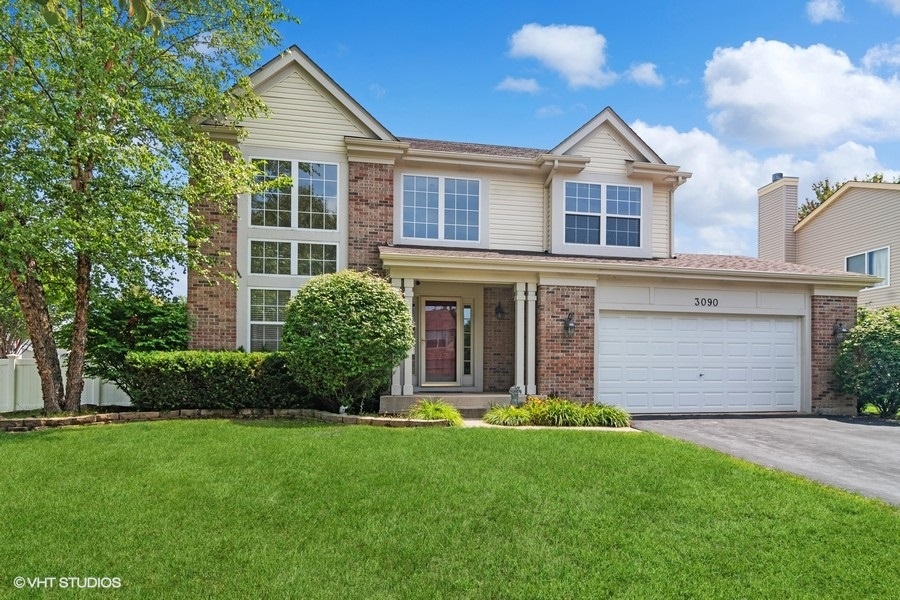 a view of a house with brick walls and a yard with plants