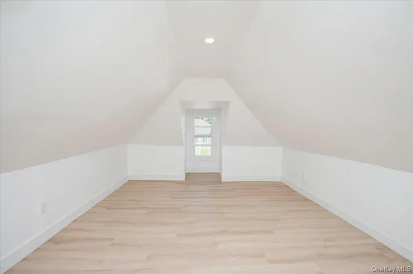 a view of an empty room with wooden floor and window