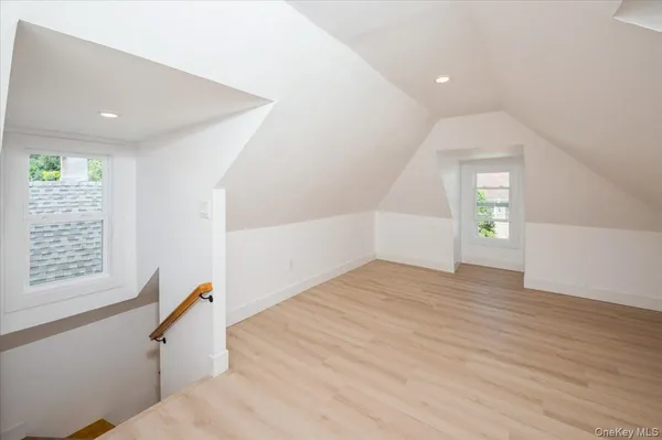a view of an empty room with wooden floor and stairs