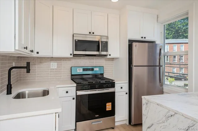 a kitchen with stainless steel appliances white cabinets and a stove top oven