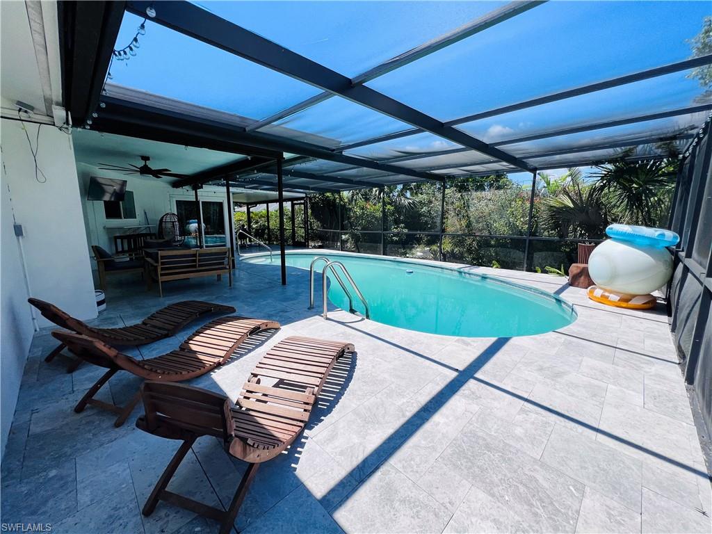 4439 Parrot Avenue Naples, FL 34104 - Photo 11 of 14 Outdoor pool featuring a sunroom, glass enclosure, and a patio