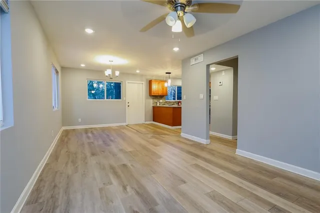 a view of empty room with wooden floor and ceiling fan