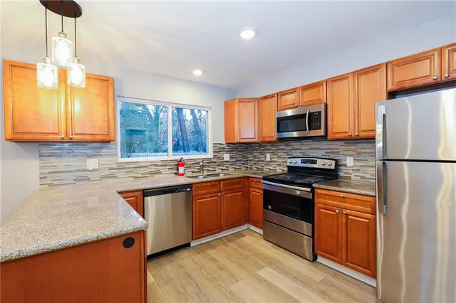 a kitchen with stainless steel appliances granite countertop a stove a sink dishwasher a refrigerator and a microwave