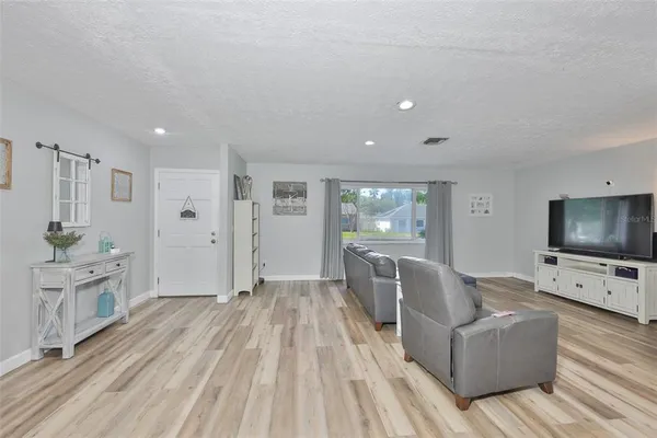 a living room with furniture a flat screen tv and a wooden floor