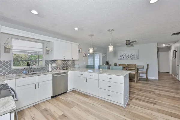 a large white kitchen with kitchen island white cabinets and wooden floor