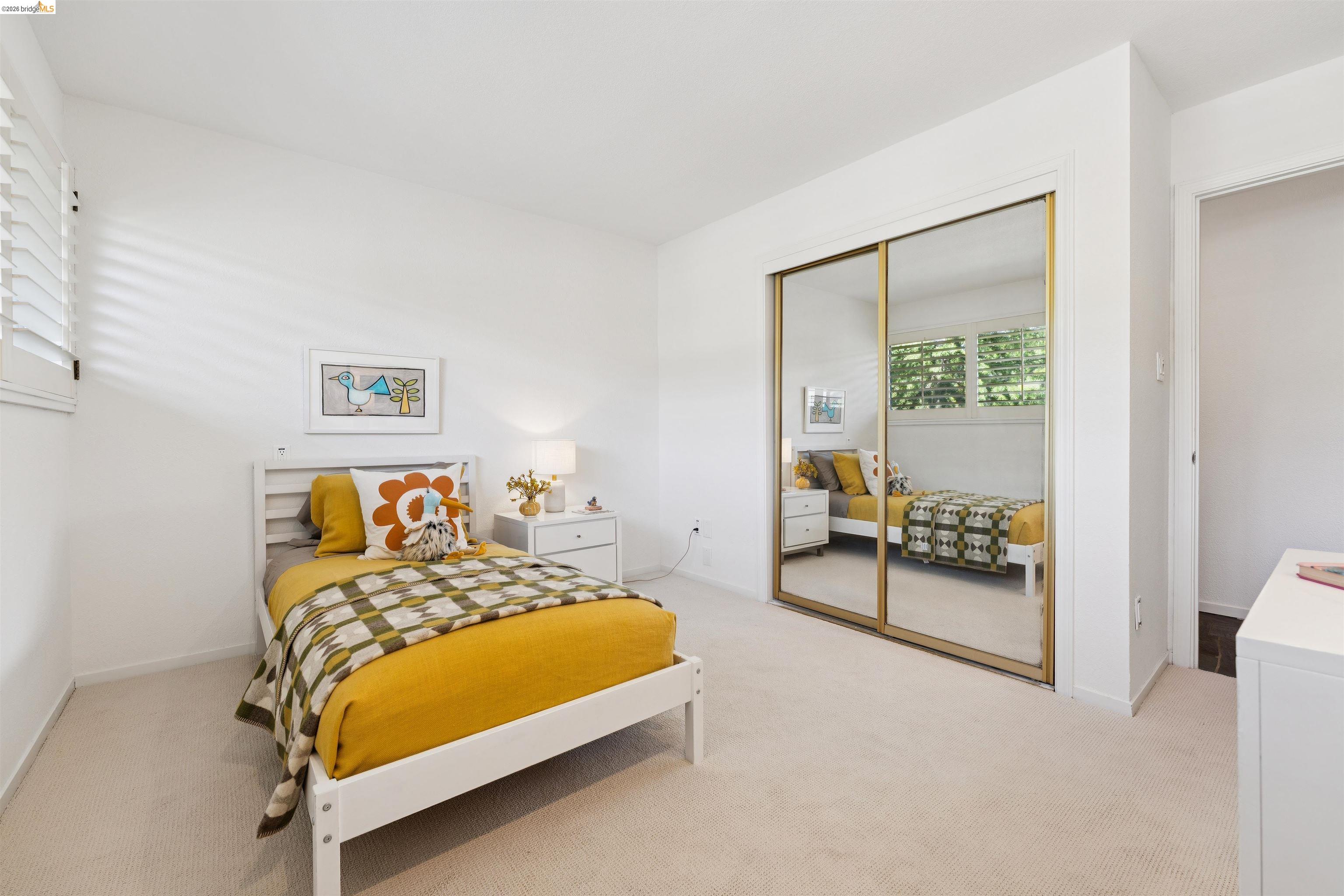 7 Jo Lin Court El Sobrante, CA 94803 - Photo 58 of 99 Light-filled bedroom featuring an expansive mirrored closet, neutral carpeting, and white plantation shutters