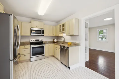 a kitchen with stainless steel appliances granite countertop white cabinets a stove a sink and dishwasher