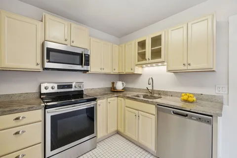 a kitchen with stainless steel appliances white cabinets white stove a microwave and a refrigerator