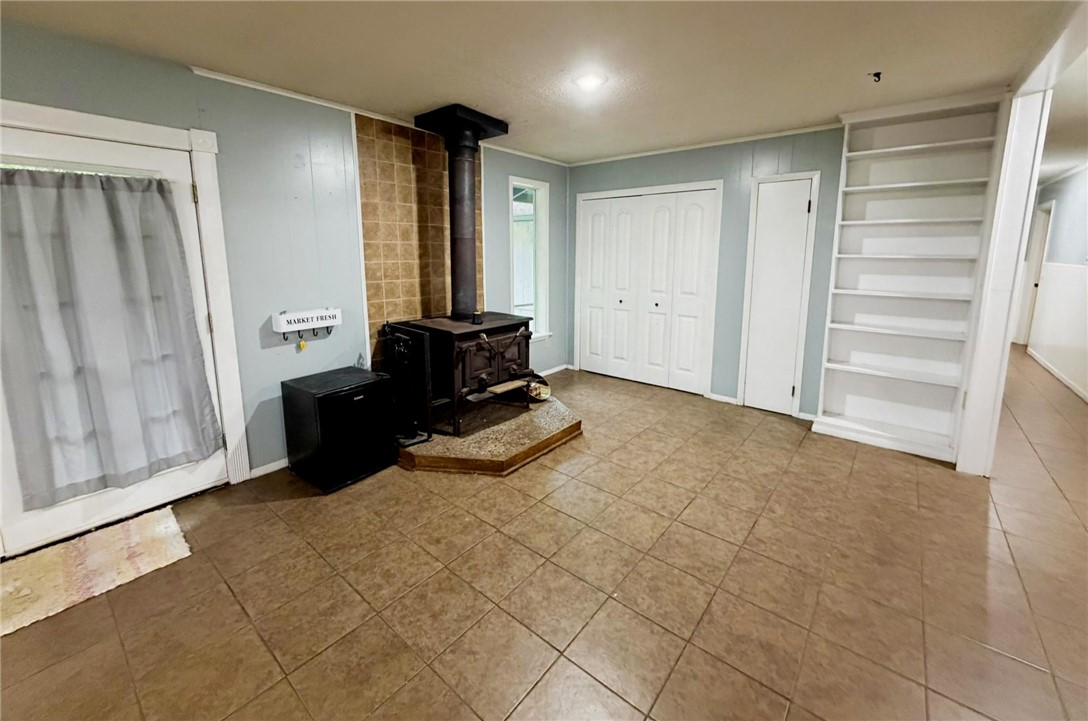 5108 Ridge Road Alma, AR 72921 - Photo 12 of 33 Spacious room featuring a central wood-burning stove on a tiled hearth, complemented by ceramic tile flooring