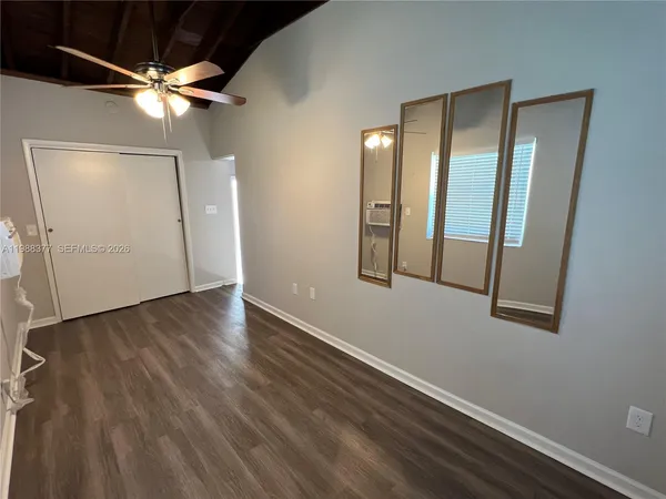 an empty room with wooden floor fan and windows