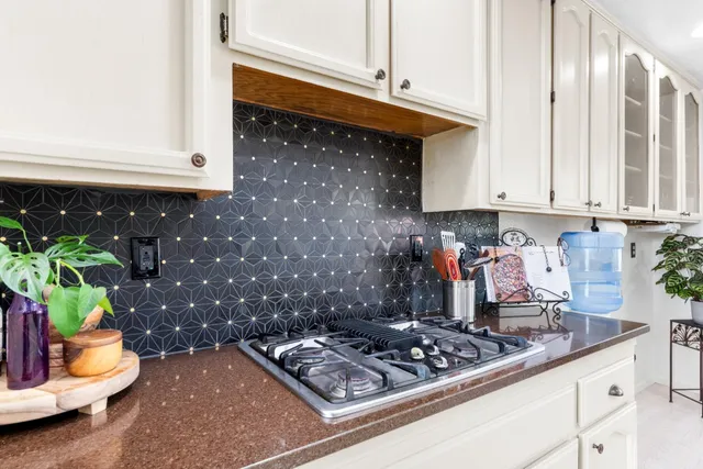 a kitchen with granite countertop a stove a sink and a white cabinets
