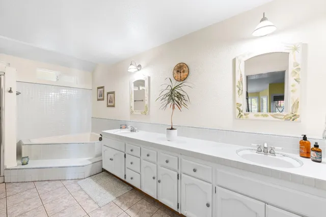 a spacious bathroom with a granite countertop sink mirror and bathtub