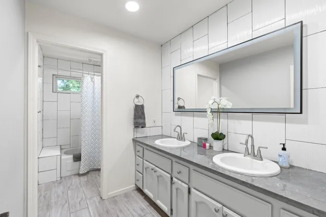 a bathroom with a granite countertop sink mirror and a shower