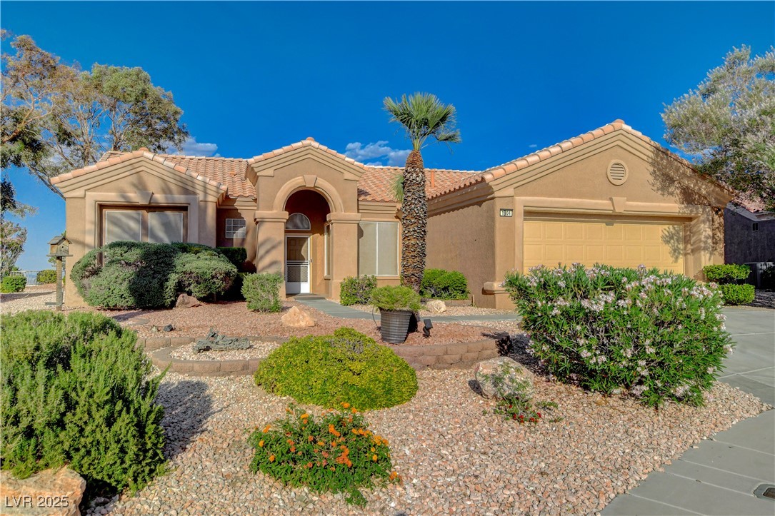 Mediterranean / spanish home featuring a tile roof, stucco siding, an attached garage, and driveway