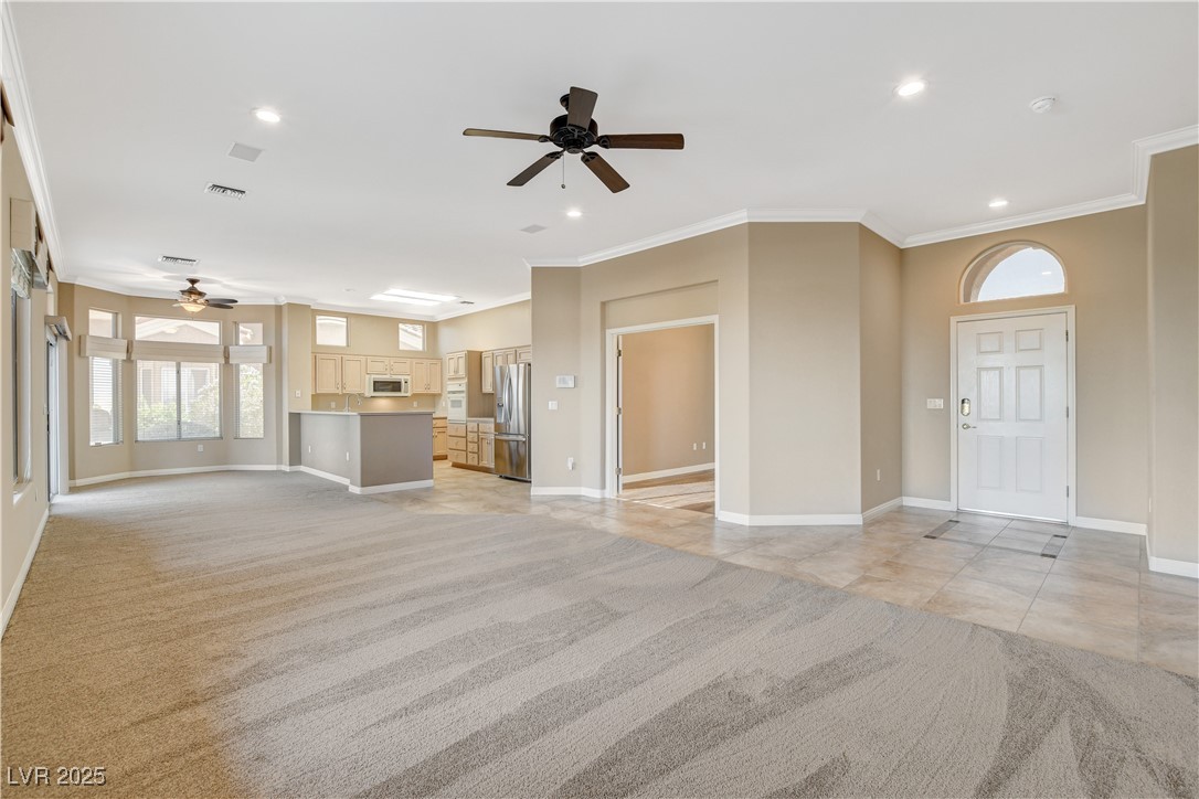 1904 Hot Oak Ridge Street Las Vegas, NV 89134 - Photo 12 of 74 Unfurnished living room featuring a ceiling fan, light carpet, recessed lighting, crown molding, and light tile patterned floors
