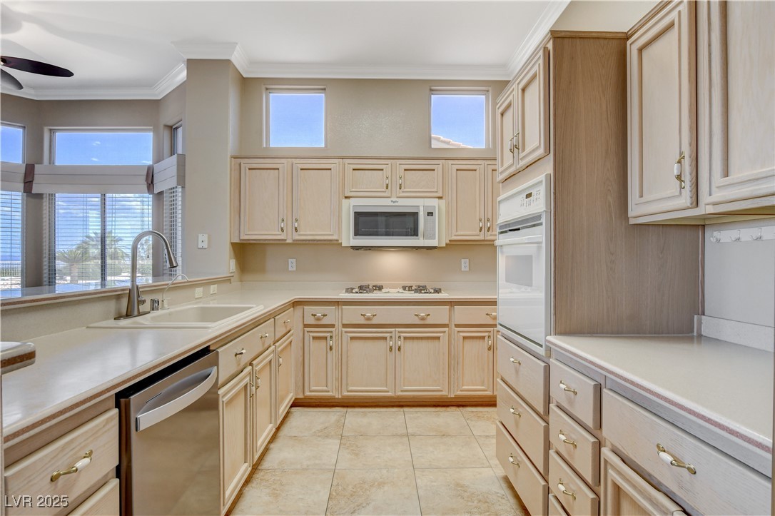 1904 Hot Oak Ridge Street Las Vegas, NV 89134 - Photo 23 of 74 Kitchen with light countertops, crown molding, light brown cabinets, plenty of natural light, and white appliances