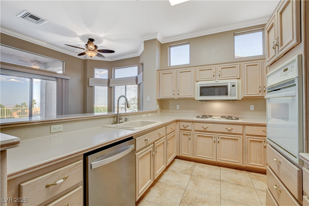 1904 Hot Oak Ridge Street Las Vegas, NV 89134 - Photo 24 of 74 Kitchen featuring crown molding, light brown cabinets, light countertops, white appliances, and a ceiling fan