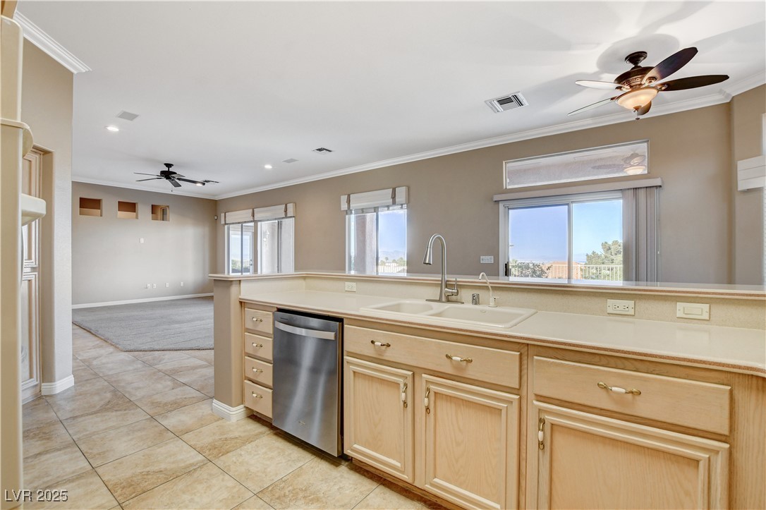 1904 Hot Oak Ridge Street Las Vegas, NV 89134 - Photo 25 of 74 Kitchen with a ceiling fan, crown molding, light brown cabinetry, light countertops, and stainless steel dishwasher