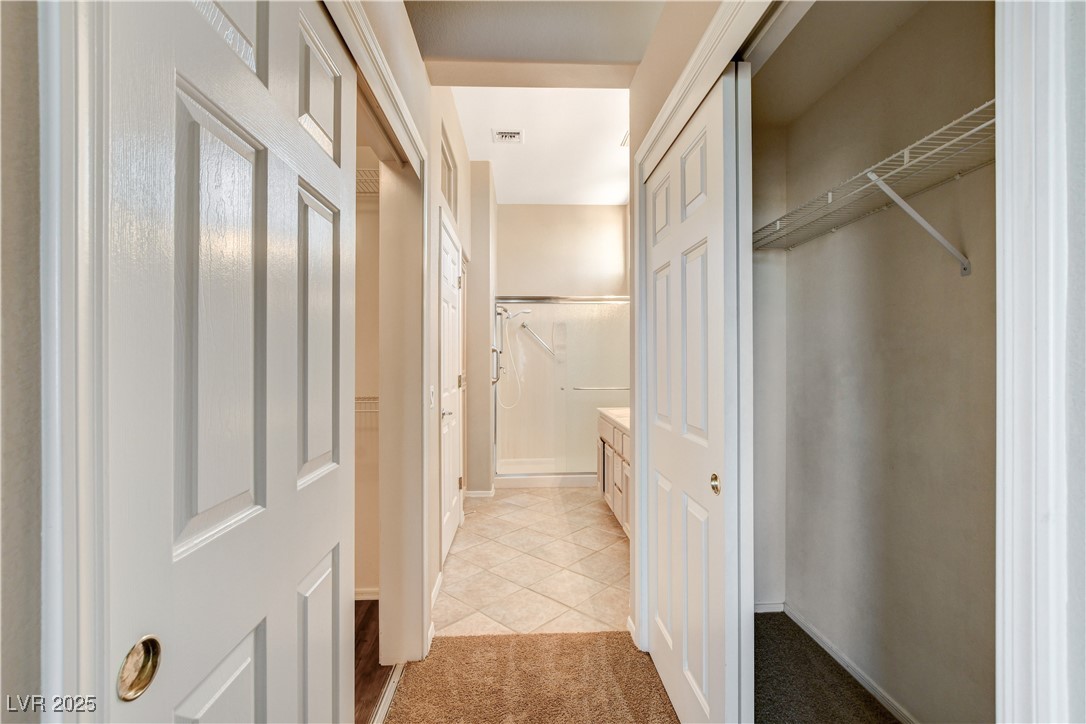 1904 Hot Oak Ridge Street Las Vegas, NV 89134 - Photo 37 of 74 Bathroom featuring a walk in closet, light tile patterned flooring, light colored carpet, and a shower