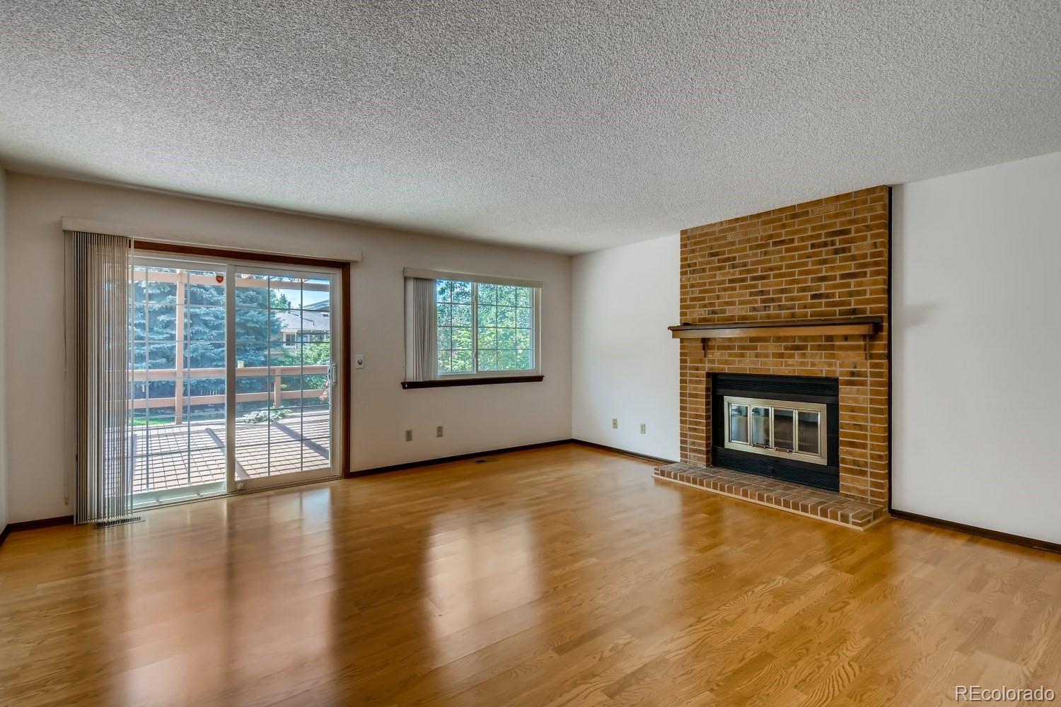 740 Prairie Ridge Road Highlands Ranch, CO 80126 - Photo 15 of 31 an empty room with wooden floor fireplace and windows