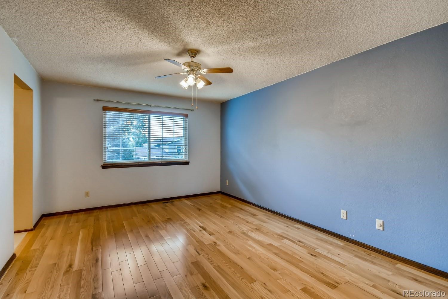 740 Prairie Ridge Road Highlands Ranch, CO 80126 - Photo 17 of 31 an empty room with wooden floor chandelier fan and windows