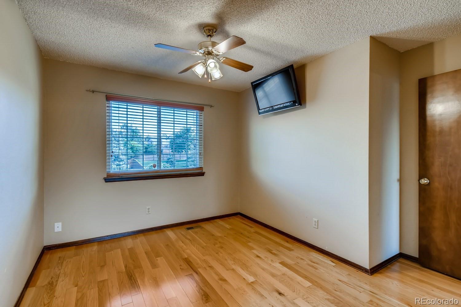 740 Prairie Ridge Road Highlands Ranch, CO 80126 - Photo 22 of 31 an empty room with wooden floor chandelier fan and windows