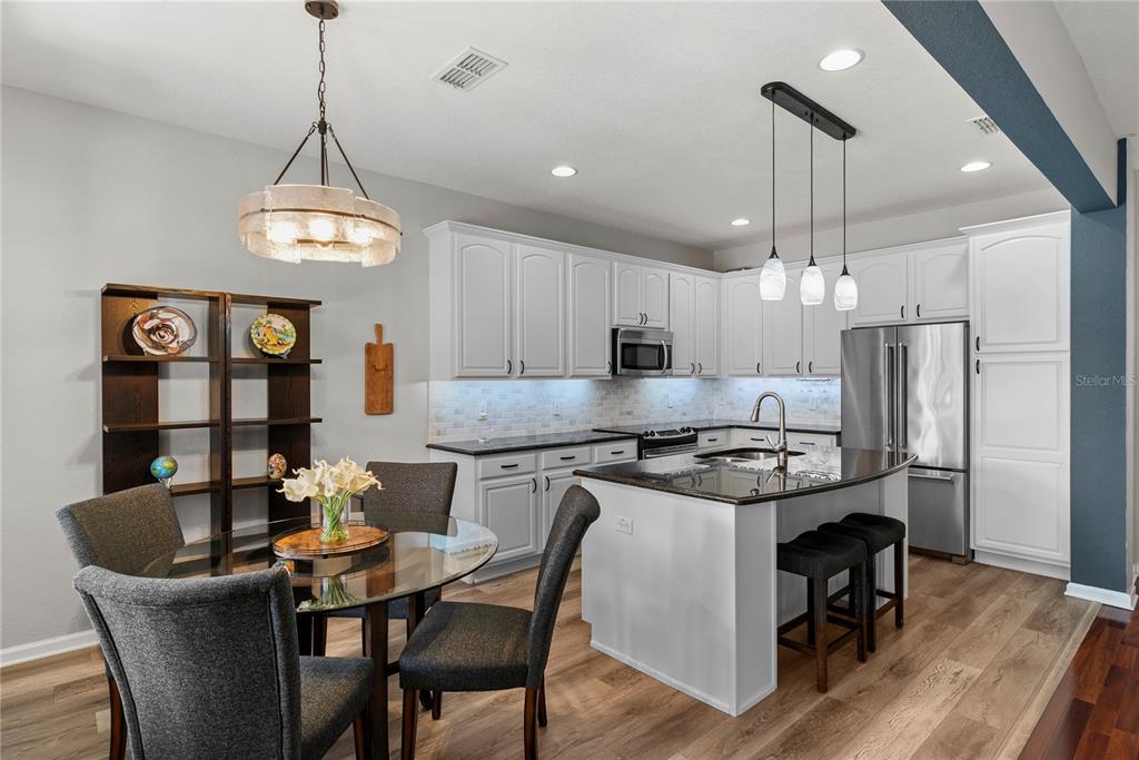 13320 Fernow Street Windermere, FL 34786 - Photo 14 of 52 a kitchen with stainless steel appliances granite countertop a stove a refrigerator a kitchen island a dining table and chairs with wooden floor