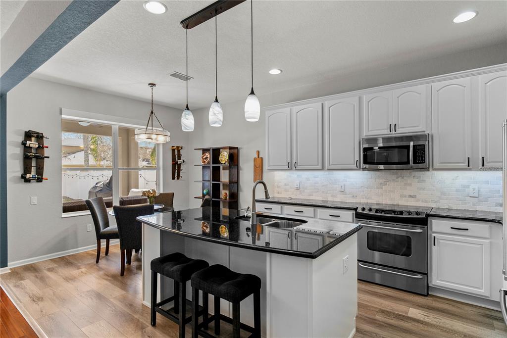 13320 Fernow Street Windermere, FL 34786 - Photo 15 of 52 a kitchen with stainless steel appliances granite countertop a stove a sink a microwave a dining table and chairs with wooden floor