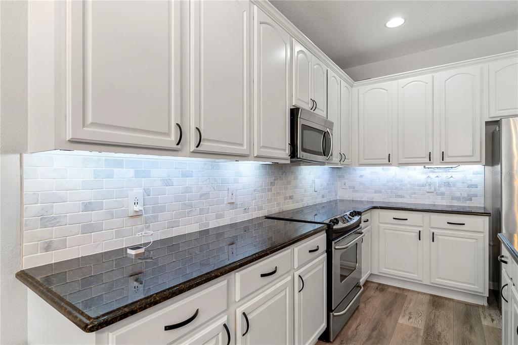 13320 Fernow Street Windermere, FL 34786 - Photo 17 of 52 a kitchen with granite countertop a sink a stove and cabinets