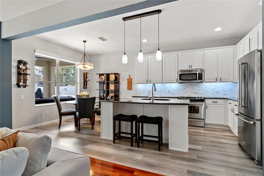 13320 Fernow Street Windermere, FL 34786 - Photo 19 of 52 a kitchen with stainless steel appliances granite countertop a refrigerator a stove a sink a dining table and chairs with wooden floor