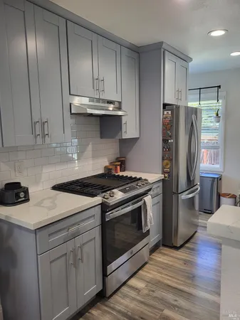 a kitchen with stainless steel appliances granite countertop a stove a refrigerator and a cabinets with wooden floors