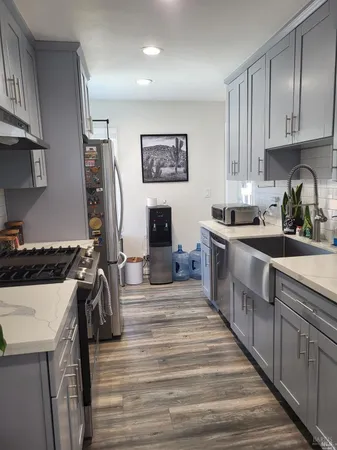 a kitchen with stainless steel appliances granite countertop a stove top oven a sink a refrigerator and white cabinets