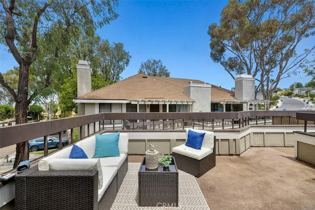 a view of a patio with couches table and chairs under an umbrella with a fire pit
