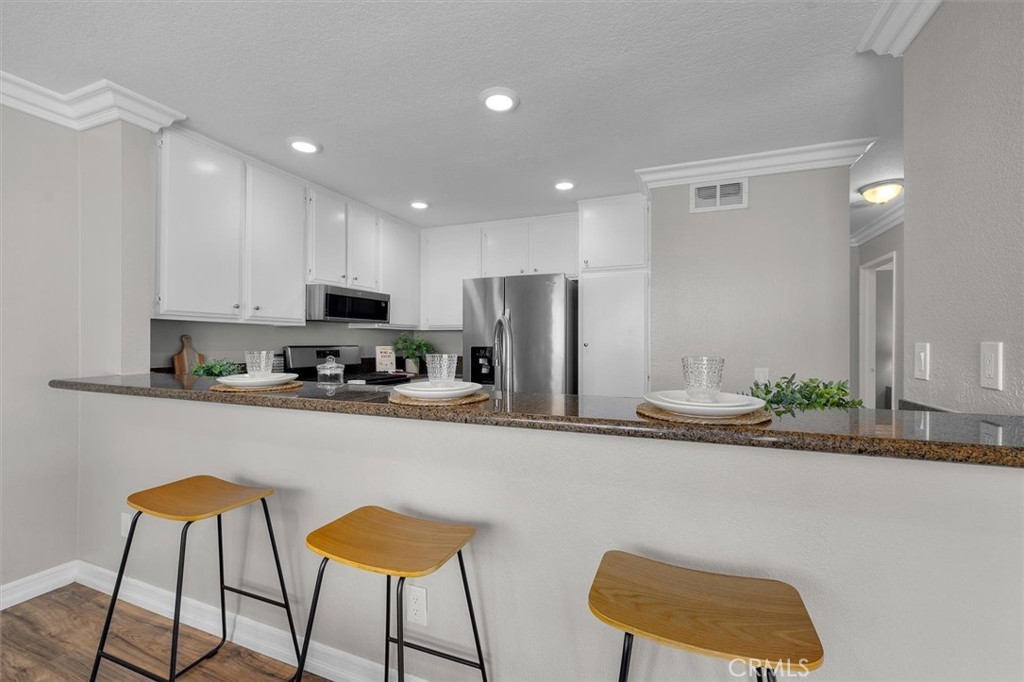 22206 Rim Pointe, Unit 7G Lake Forest, CA 92630 - Photo 16 of 39 a kitchen with stainless steel appliances granite countertop a refrigerator and a stove top oven with white cabinets