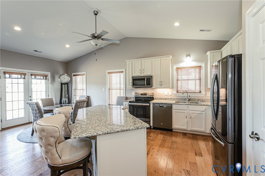 7622 Settlers Ridge Court Henrico, VA 23231 - Photo 13 of 43 a kitchen with kitchen island granite countertop a stove top oven a sink dishwasher a dining table and chairs with wooden floor