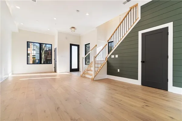 a view of an empty room with wooden floor and stairs