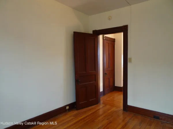 a view of an empty room with wooden floor and closet
