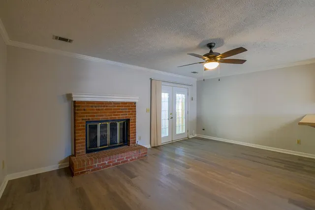 an empty room with wooden floor fireplace and windows