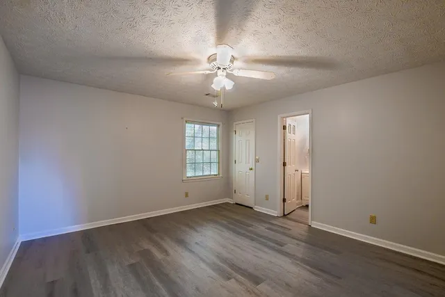 an empty room with wooden floor ceiling fan and windows