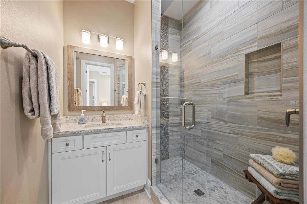 2 Gulf Boulevard Indian Rocks Beach, FL 33785 - Photo 36 of 79 a bathroom with a granite countertop sink a mirror and shower