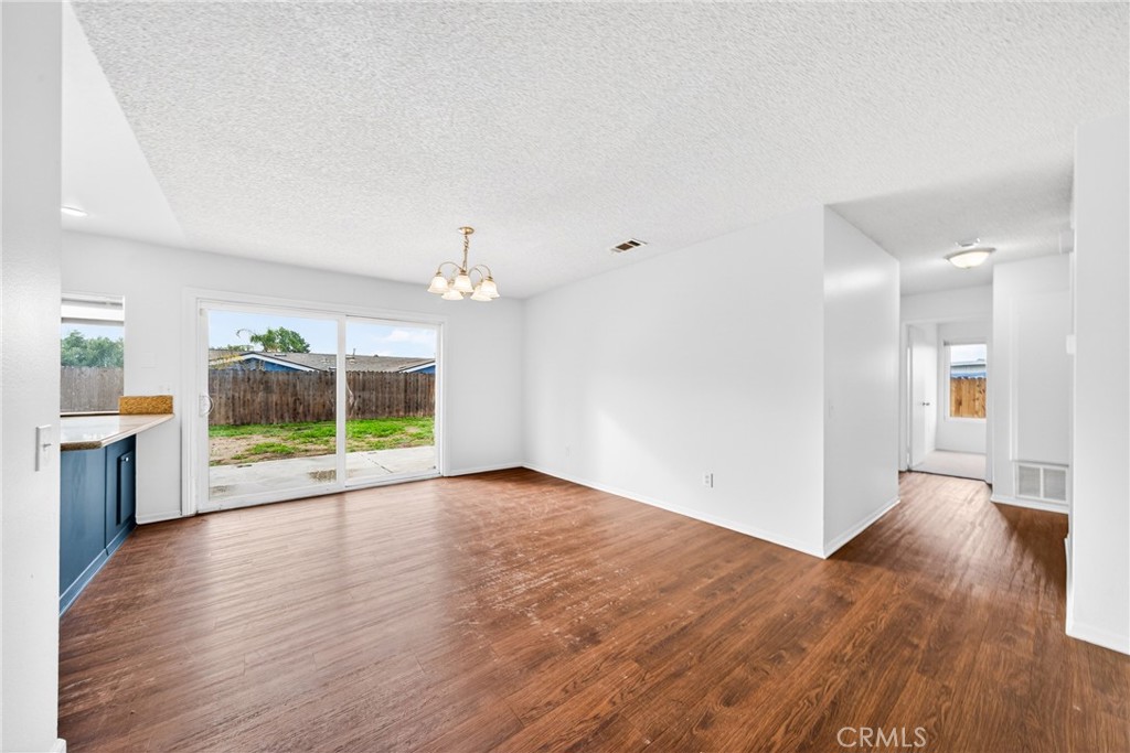 24867 Bower Street Moreno Valley, CA 92553 - Photo 21 of 46 a view of an empty room with wooden floor and a kitchen