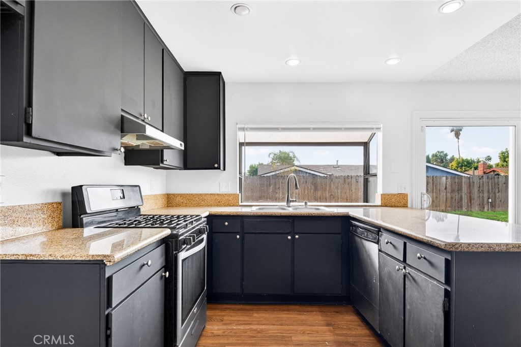 24867 Bower Street Moreno Valley, CA 92553 - Photo 23 of 46 a kitchen with a sink a stove and cabinets