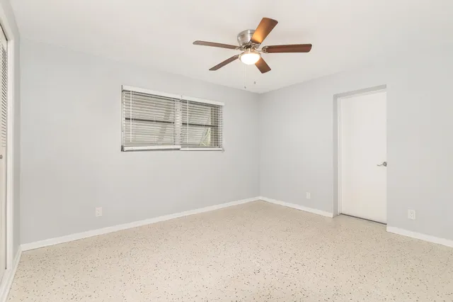 an empty room with a window and a fan