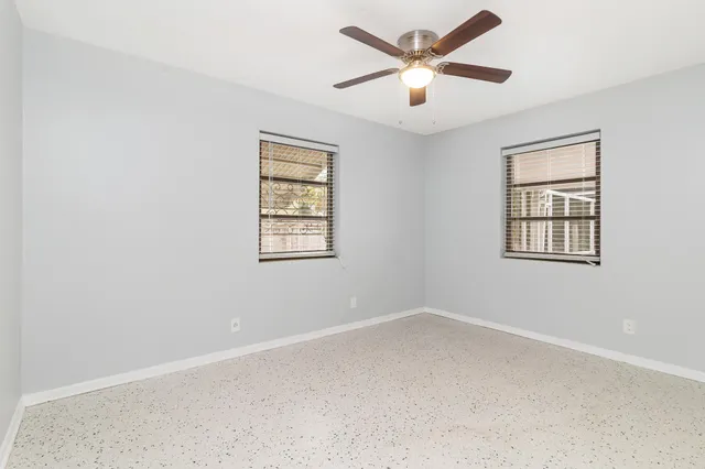 an empty room with a window and a fan