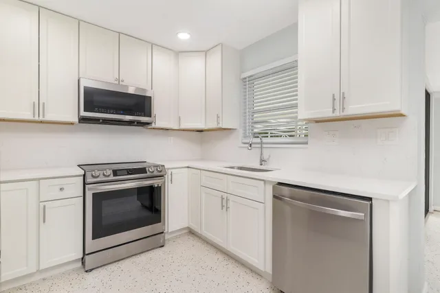 a kitchen with granite countertop white cabinets and stainless steel appliances